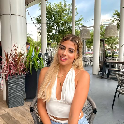 Carla Diab sitting in chair in sunshine in white dress